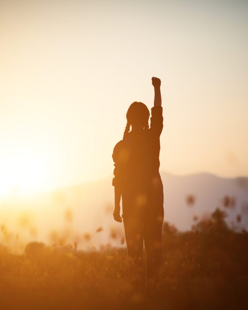 Silhouette of woman praying over beautiful sky background